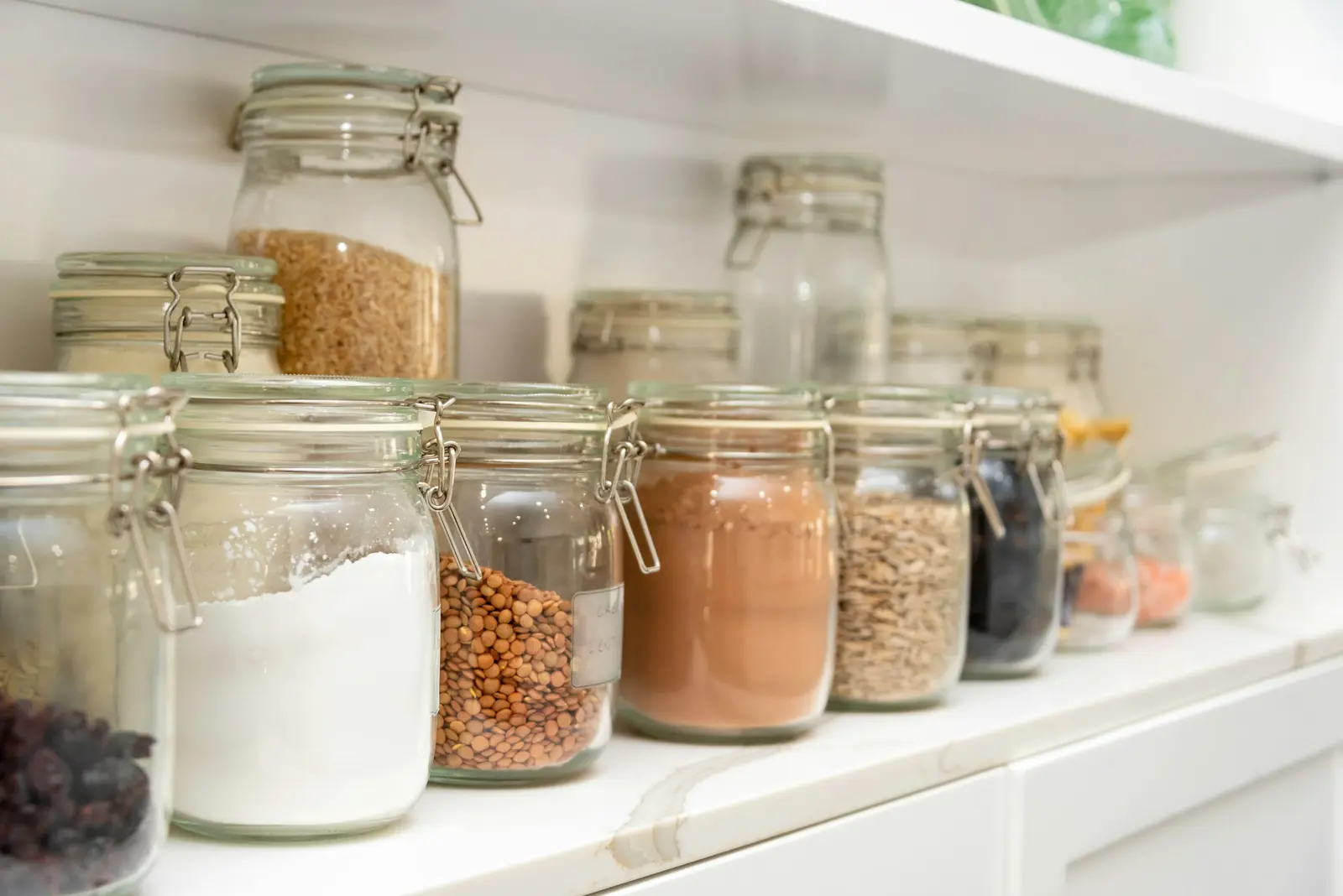 Neatly arranged glass jars on a white shelf